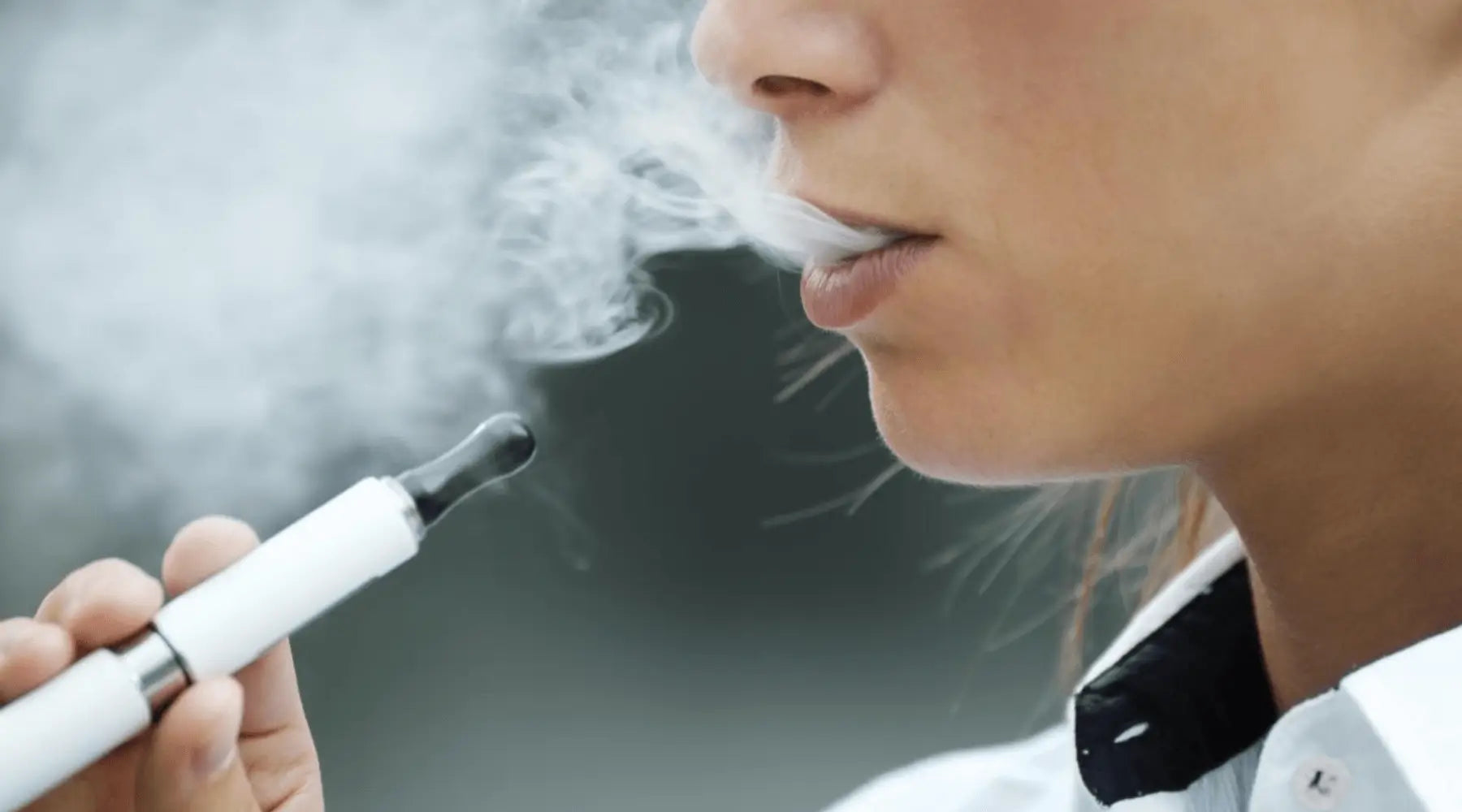 Person exhaling vapor from an e-cigarette with nic salt and 50ml e-liquids